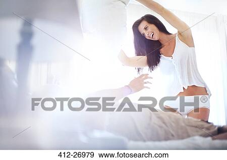 Playful couple on bed in sunny bedroom View Large Photo Image Stock Photo - Playful couple on bed in sunny bedroom. Fotosearch