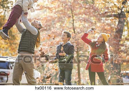 Playful father and children playing in autumn leaves View Large Photo Image Stock Photograph - Playful father and children playing in autumn leaves. Fotosearch