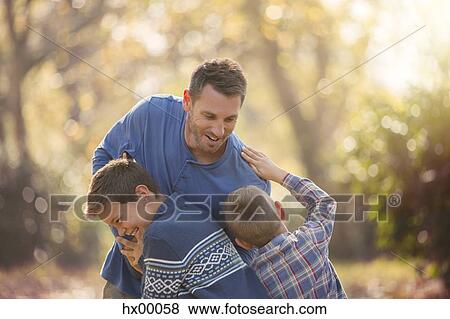 Playful father and sons rough housing outdoors View Large Photo Image Stock Photo - Playful father and sons rough housing outdoors. Fotosearch