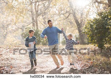 Playful father and sons running on trail in woods View Large Photo Image Picture - Playful father and sons running on trail in woods. Fotosearch
