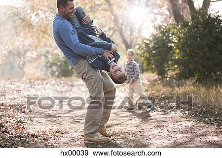 Playful father lifting son upside-down on path in woods View Large Photo Image Stock Photo - Playful father lifting son upside-down on path in woods. Fotosearch