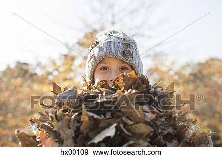 Stock Photo - Portrait boy holding bunch of autumn leaves. Fotosearch