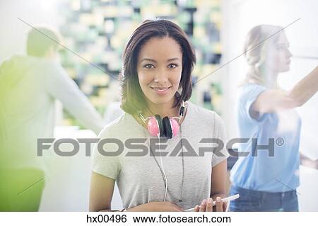 Stock Photograph - Portrait confident creative businesswoman with headphones in office. Fotosearch