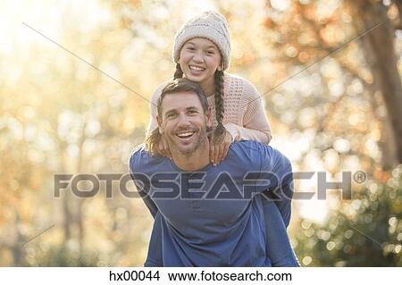 Portrait enthusiastic father piggybacking daughter outdoors View Large Photo Image Picture - Portrait enthusiastic father piggybacking daughter outdoors. Fotosearch