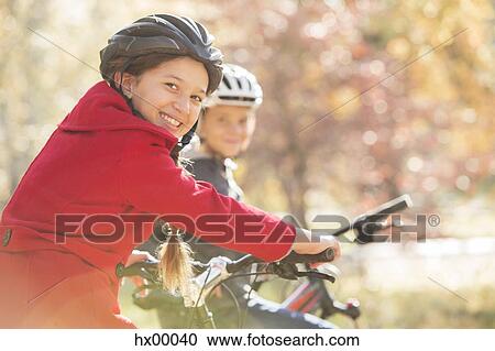 Stock Image - Portrait enthusiastic girl bike riding with boy. Fotosearch