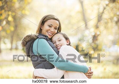 Stock Photo - Portrait of smiling mother and daughter hugging outdoors. Fotosearch