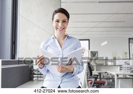 Portrait smiling businesswoman holding report in office View Large Photo Image Picture - Portrait smiling businesswoman holding report in office. Fotosearch
