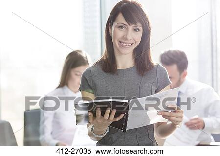 Portrait smiling businesswoman holding report View Large Photo Image Stock Photography - Portrait smiling businesswoman holding report. Fotosearch