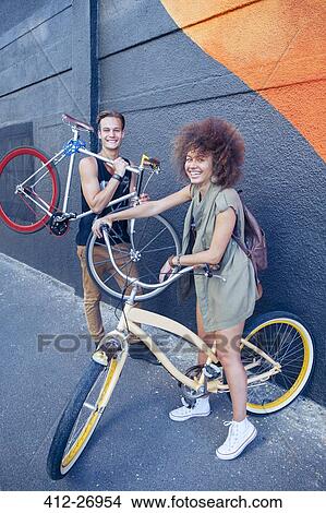 Portrait smiling friends with bicycles next to urban wall View Large Photo Image Picture - Portrait smiling friends with bicycles next to urban wall. Fotosearch