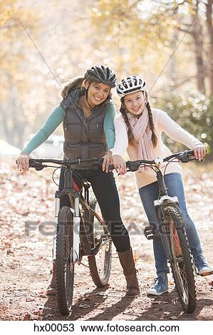 Portrait smiling mother and daughter on mountain bikes in woods View Large Photo Image Stock Image - Portrait smiling mother and daughter on mountain bikes in woods. Fotosearch