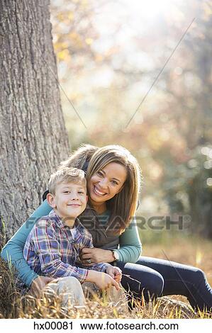 Portrait smiling mother and son at tree trunk in autumn woods View Large Photo Image Stock Image - Portrait smiling mother and son at tree trunk in autumn woods. Fotosearch
