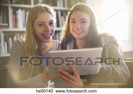 Stock Image - Portrait smiling teenage girls using digital tablet. Fotosearch