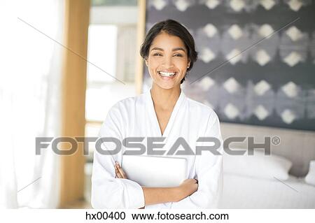 Stock Image - Portrait smiling woman in bathrobe holding digital tablet. Fotosearch
