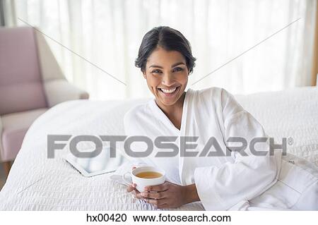 Portrait smiling woman in bathrobe drinking tea on bed View Large Photo Image Stock Image - Portrait smiling woman in bathrobe drinking tea on bed. Fotosearch