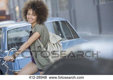 Portrait smiling woman with afro on bicycle in urban street View Large Photo Image Stock Photo - Portrait smiling woman with afro on bicycle in urban street. Fotosearch