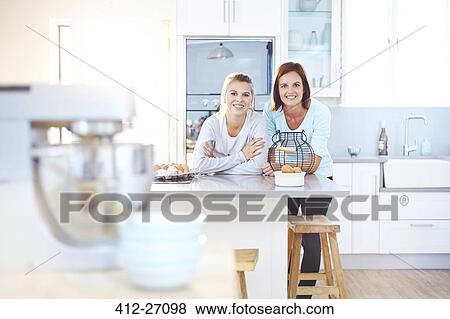 Stock Photo - Portrait smiling women leaning on kitchen counter. Fotosearch