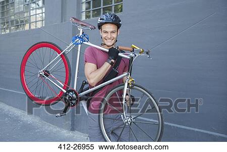 Portrait smiling young man carrying bicycle on urban sidewalk View Large Photo Image Stock Photography - Portrait smiling young man carrying bicycle on urban sidewalk. Fotosearch