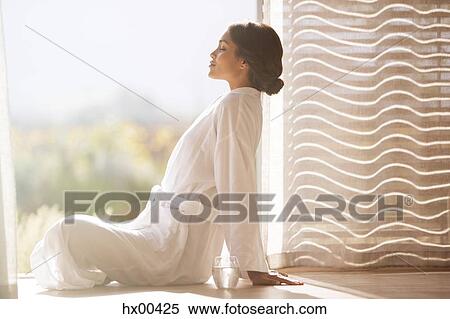 Serene woman in bathrobe sitting cross-legged at sunny doorway View Large Photo Image Stock Photography - Serene woman in bathrobe sitting cross-legged at sunny doorway. Fotosearch