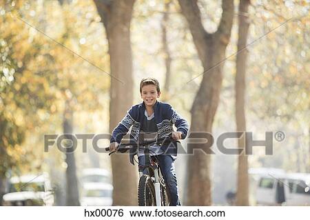 Smiling boy bike riding in park View Large Photo Image Stock Photograph - Smiling boy bike riding in park. Fotosearch