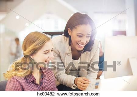 Stock Image - Smiling businesswoman using computer in sunny office. Fotosearch