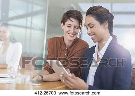 Smiling businesswomen using digital tablet in office View Large Photo Image Stock Image - Smiling businesswomen using digital tablet in office. Fotosearch