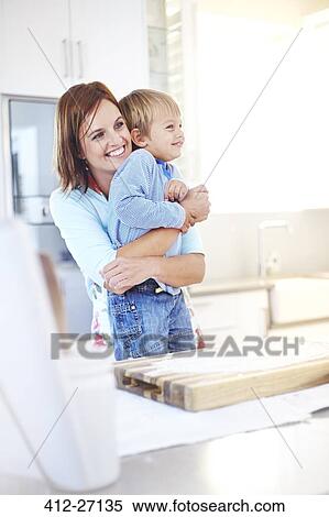 Smiling mother hugging son in kitchen View Large Photo Image Stock Photography - Smiling mother hugging son in kitchen. Fotosearch