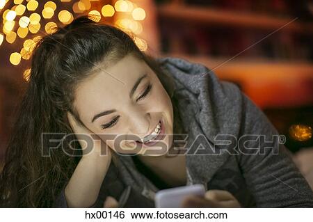 Stock Photograph - Smiling teenage girl texting with cell phone. Fotosearch