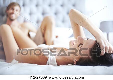 Stock Photo - Smiling woman laying on bed with man. Fotosearch