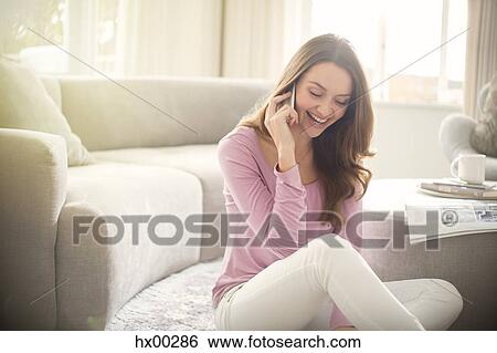 Smiling woman talking on cell phone in living room View Large Photo Image Stock Photograph - Smiling woman talking on cell phone in living room. Fotosearch