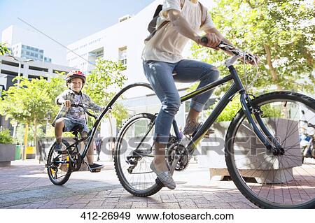 Son in helmet riding tandem bicycle with mother in urban park View Large Photo Image Stock Photo - Son in helmet riding tandem bicycle with mother in urban park. Fotosearch