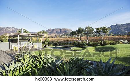 Sunny modern patio and yard with mountains in background View Large Photo Image Stock Image - Sunny modern patio and yard with mountains in background. Fotosearch