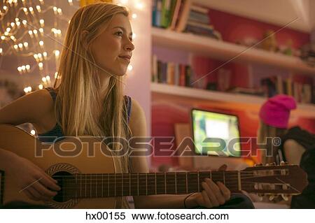 Teenage girl playing guitar in bedroom View Large Photo Image Stock Photography - Teenage girl playing guitar in bedroom. Fotosearch