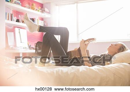 Stock Photo - Teenage girl playing guitar on bed. Fotosearch