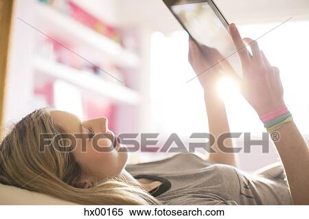 Teenage girl using digital tablet in sunny bedroom View Large Photo Image Stock Photography - Teenage girl using digital tablet in sunny bedroom. Fotosearch