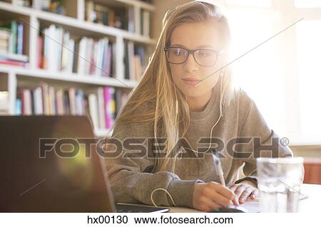Teenage girl with headphones doing homework with laptop View Large Photo Image Stock Image - Teenage girl with headphones doing homework with laptop. Fotosearch