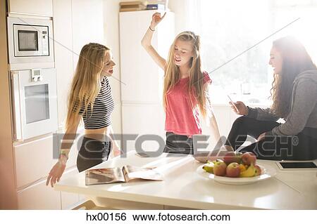 Stock Photograph - Teenage girls dancing in sunny kitchen. Fotosearch