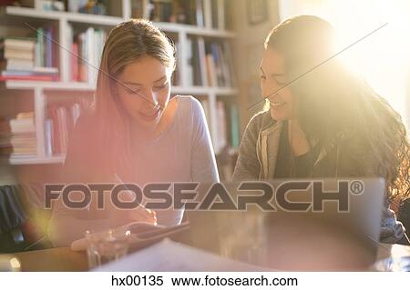 Stock Photography - Teenage girls doing homework in sunny room. Fotosearch