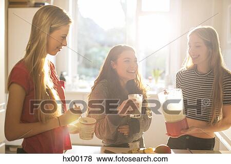 Teenage girls making smoothie in sunny kitchen View Large Photo Image Stock Photo - Teenage girls making smoothie in sunny kitchen. Fotosearch