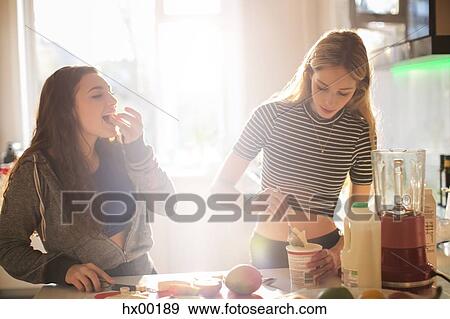 Teenage girls making smoothie in sunny kitchen View Large Photo Image Stock Photo - Teenage girls making smoothie in sunny kitchen. Fotosearch