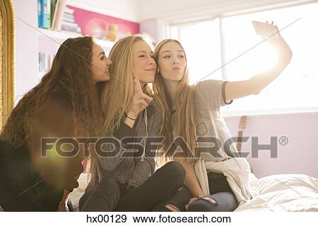 Stock Photo - Teenage girls posing for selfie with camera phone. Fotosearch