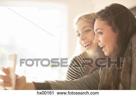 Stock Image - Teenage girls taking selfie with camera phone. Fotosearch