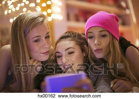 Stock Image - Teenage girls taking selfie with camera phone. Fotosearch