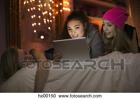 Teenage girls using digital tablet on bed View Large Photo Image Stock Image - Teenage girls using digital tablet on bed. Fotosearch