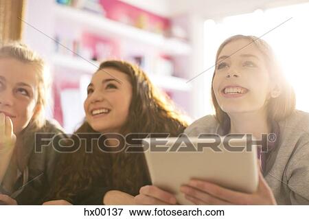 Stock Photo - Teenage girls using digital tablet looking up. Fotosearch