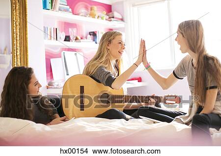 Teenage girls with guitar high fiving on bed View Large Photo Image Picture - Teenage girls with guitar high fiving on bed. Fotosearch