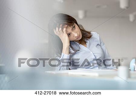 Stock Photo - Tired businesswoman with head in hands looking away. Fotosearch