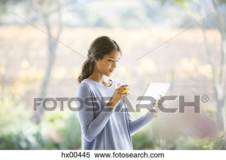 Woman drinking orange juice and using digital tablet View Large Photo Image Stock Photography - Woman drinking orange juice and using digital tablet. Fotosearch