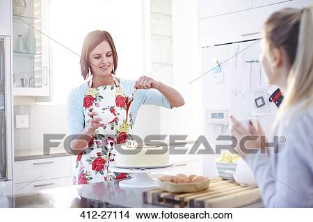 Picture - Woman frosting cake baking in kitchen. Fotosearch