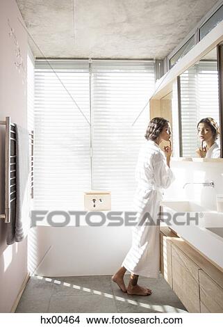 Woman in bathrobe examining face in bathroom mirror View Large Photo Image Picture - Woman in bathrobe examining face in bathroom mirror. Fotosearch