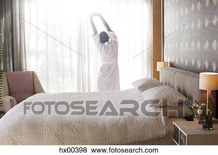 Woman in bathrobe stretching with arms raised in bedroom View Large Photo Image Stock Photo - Woman in bathrobe stretching with arms raised in bedroom. Fotosearch